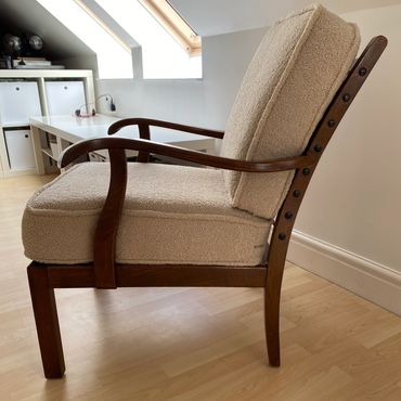 Elegant wooden armchair with beige cushioned seat and backrest.