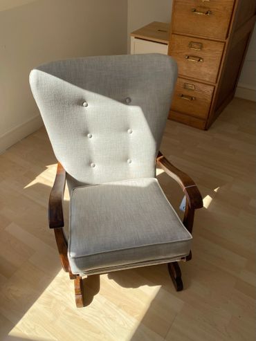 Vintage wooden armchair with light gray fabric upholstery in sunlight.
