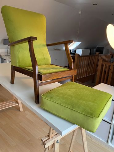 Wooden armchair with green upholstery and matching cushion on a white table.