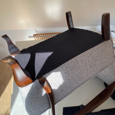 Upside-down padded bench with wooden legs.