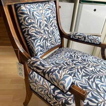Wooden armchair with blue and white floral upholstery.
