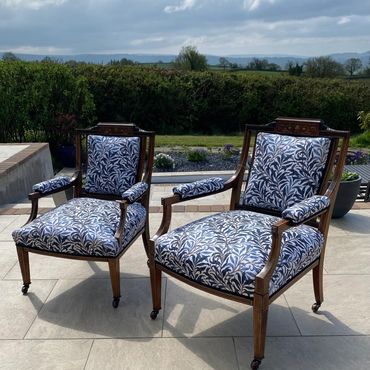 Two vintage wooden armchairs with blue patterned upholstery outdoors.