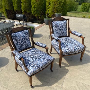 Two elegant wooden chairs with blue and white patterned cushions on a patio.