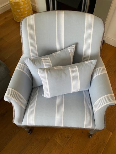 Light blue striped armchair with matching cushions on wooden floor.