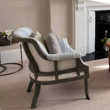 Elegant armchair with striped upholstery by a fireplace in a cozy living room.