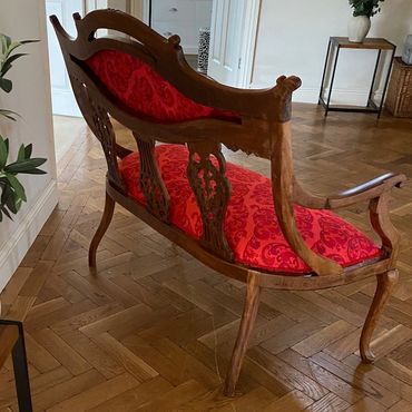 Elegant wooden bench with red upholstered cushions in a stylish room.