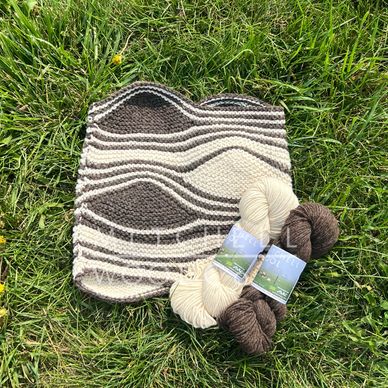 a brown and white hand knit cowl sits in the grass