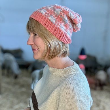 SHERRY WEARS A GINGHAM PINK HAT IN THE BARN WITH LAMBS IN THE BACKGROUND