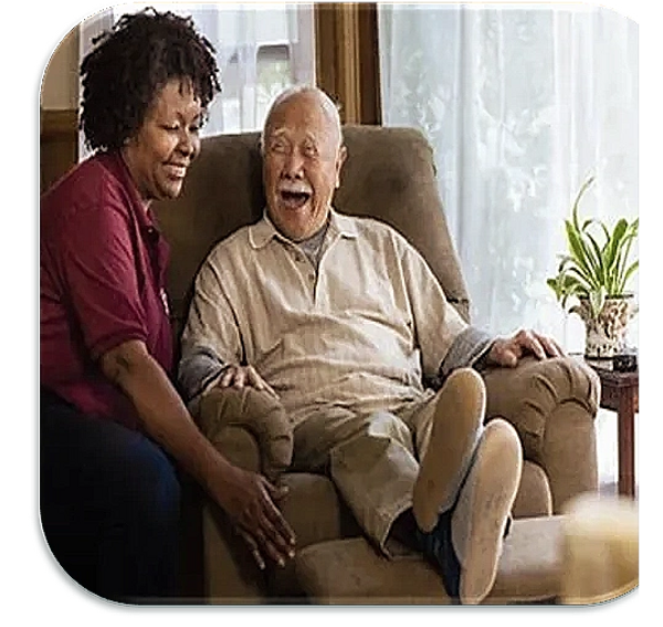 Caregiver, Samantha, joyfully assists her senior male client into his recliner at his home.