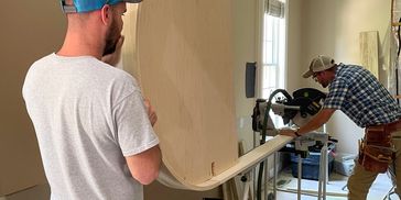 Two men working on a woodworking project indoors.