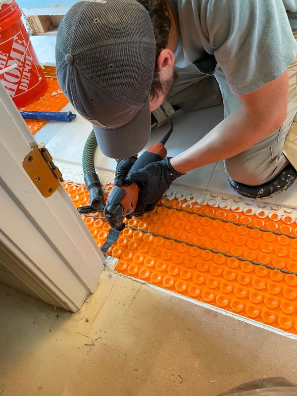 Person installing orange underfloor heating system.