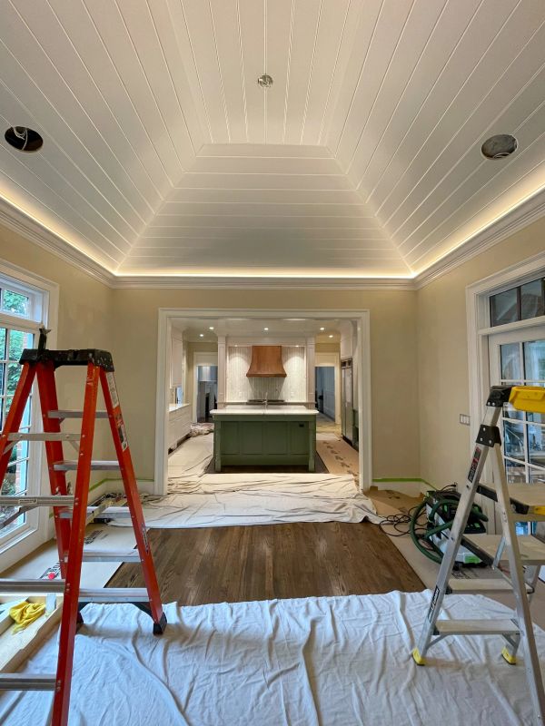 Room under renovation with ladders and covered floors.