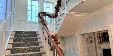 Elegant staircase decorated with garland and teddy bears.