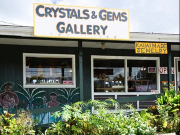 Exterior of a Crystals & Gems Gallery with tropical plants and painted murals.