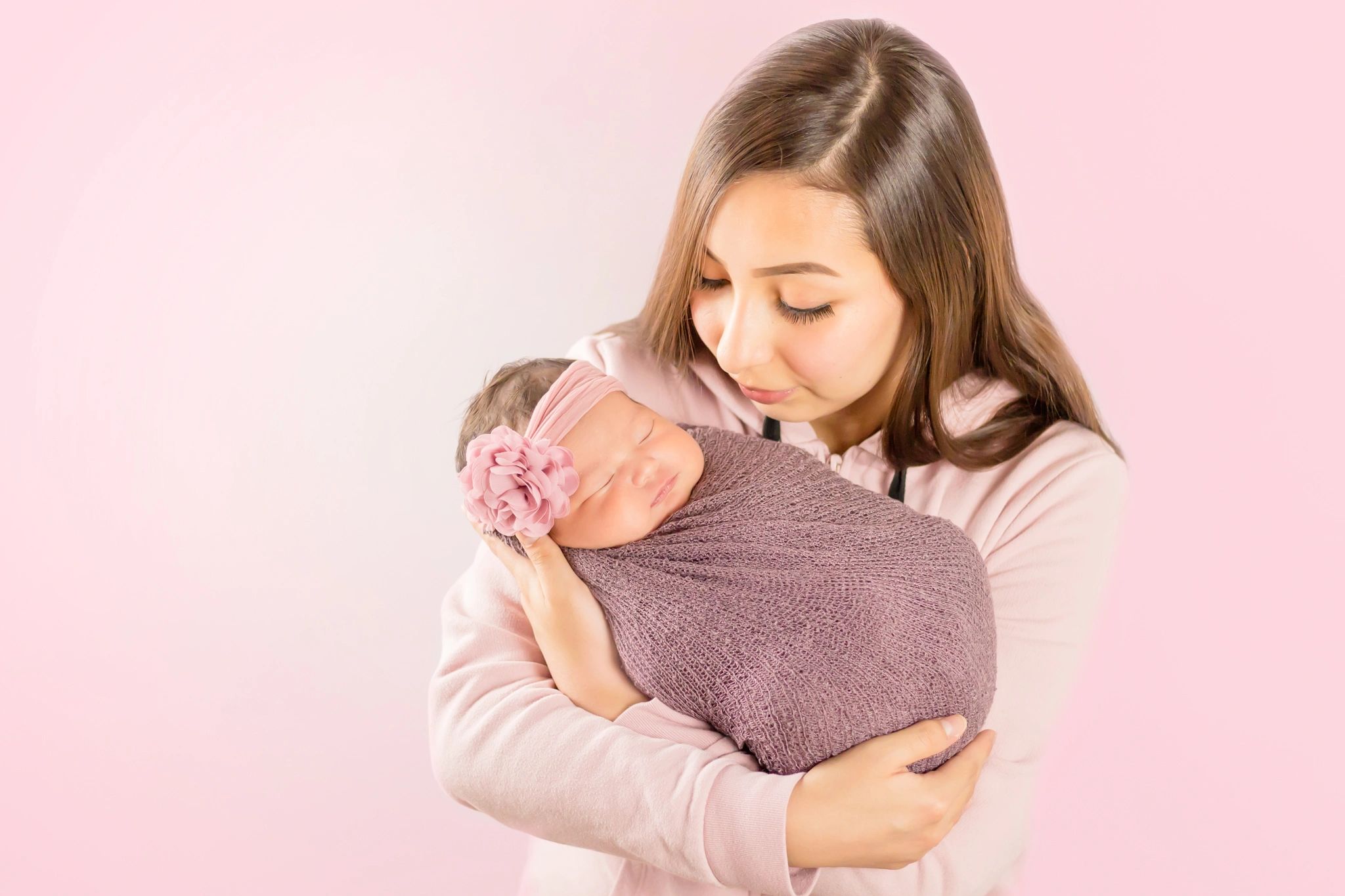 A mother lovingly holding her sleeping newborn baby.