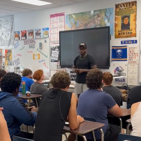 Teacher speaking to attentive high school students in classroom.