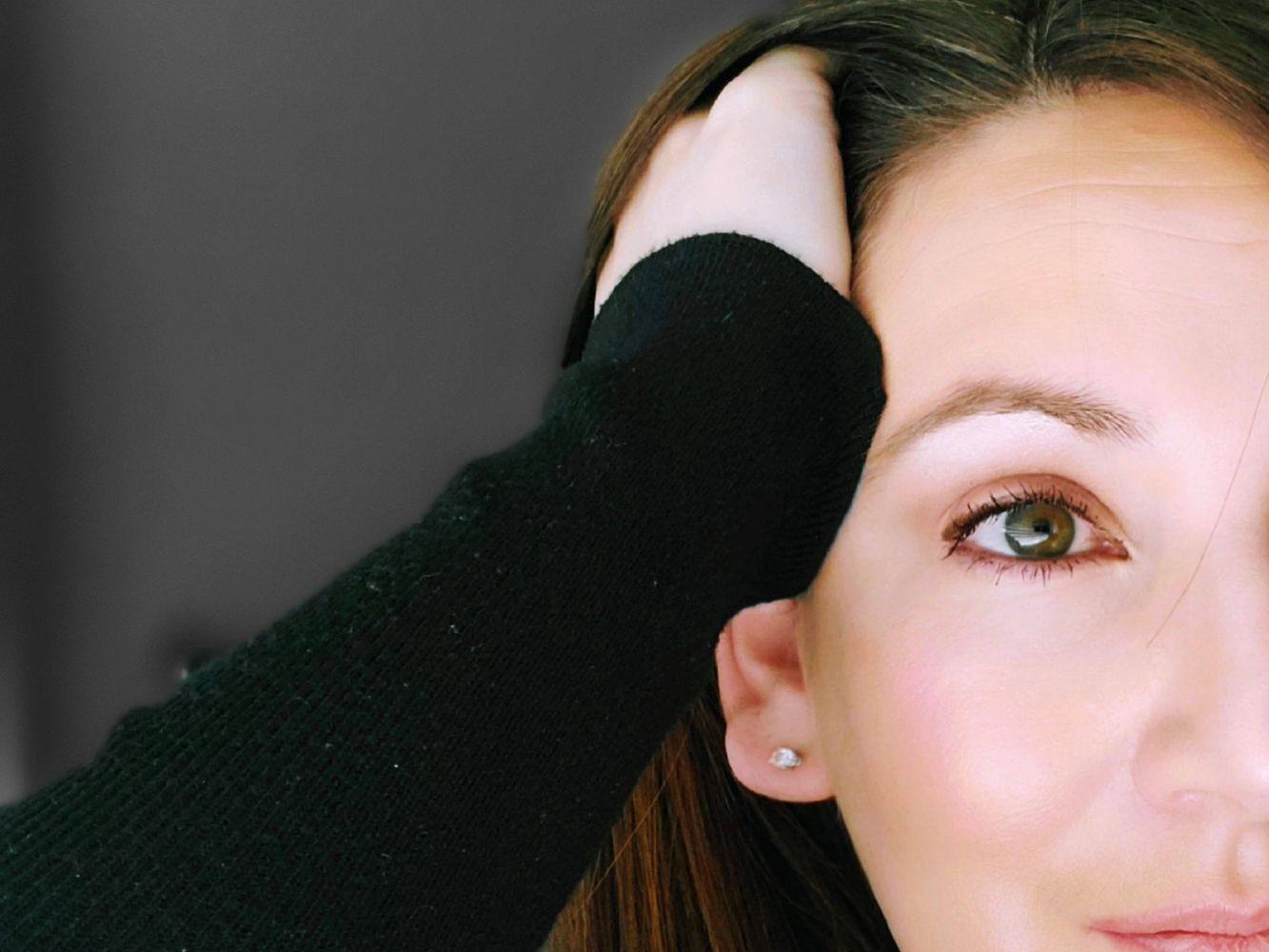 Close-up portrait of a woman with green eyes and a thoughtful expression.