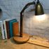 A Folk Art style lamp with a wooden base and carved arm. The fixed shade is a great golden colour.  