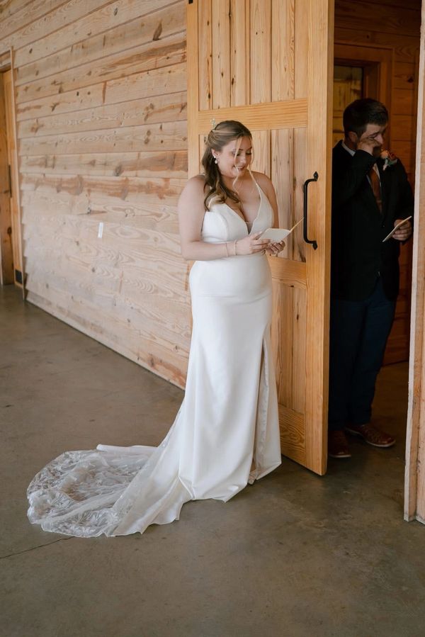 Bride and groom share a private moment reading notes behind a wooden door.