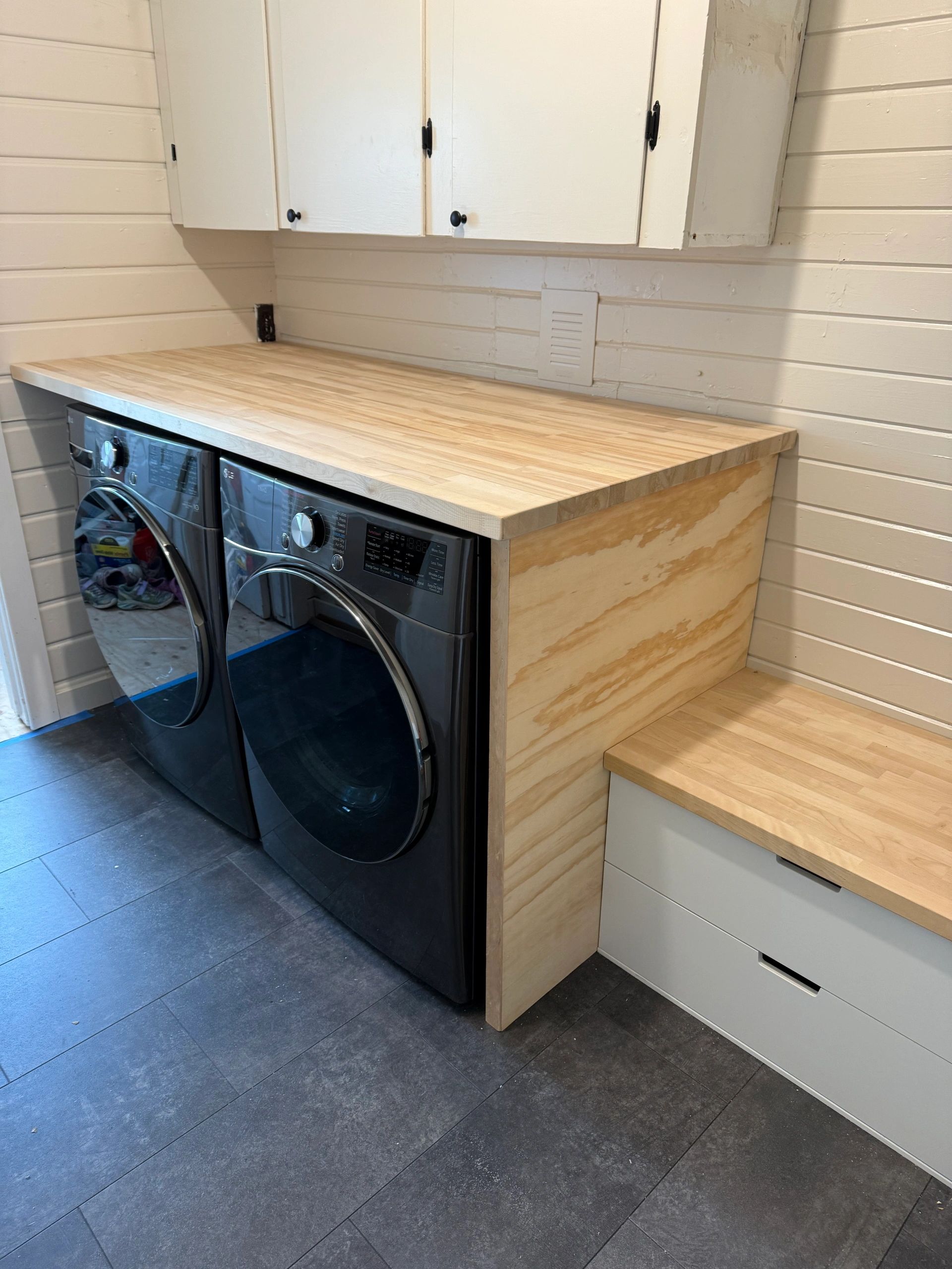 Laundry area with washer, dryer, and wooden countertop.