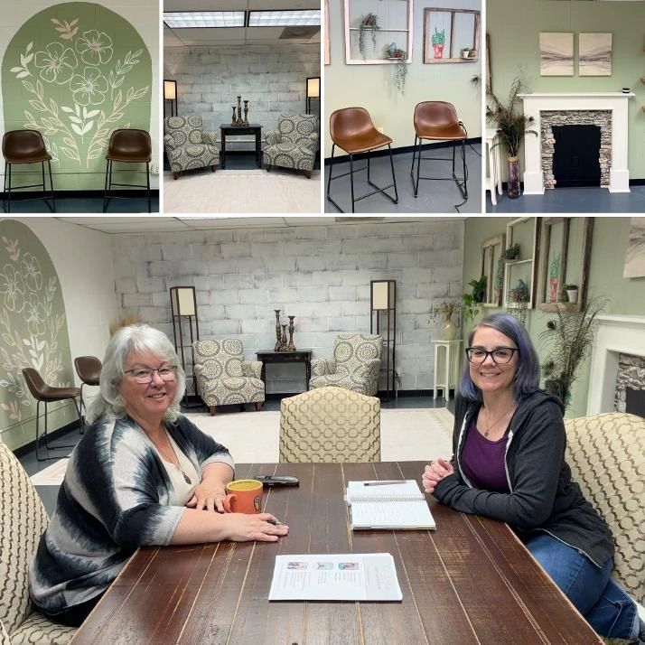 Two women smiling at a wooden table in a cozy room.