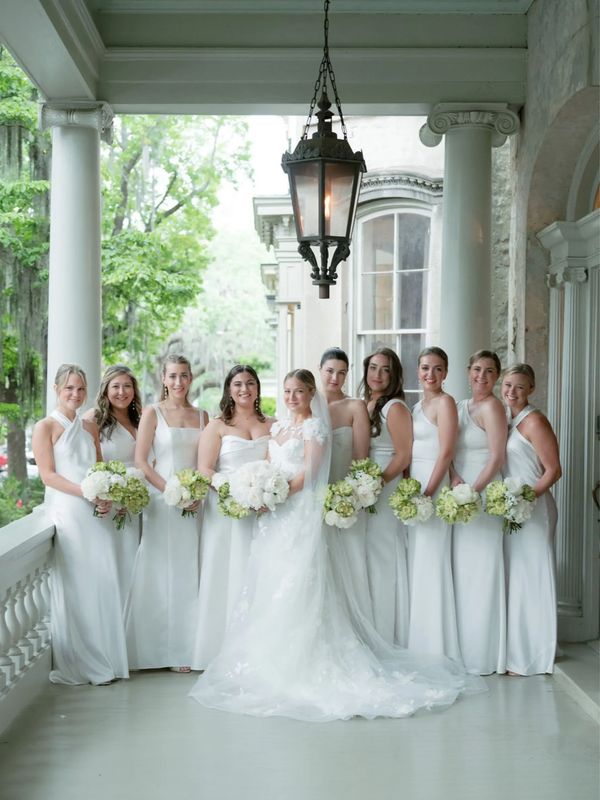 Bride and bridesmaids in white gowns on a historic Savannah, GA with wedding makeup by MANDAGLO