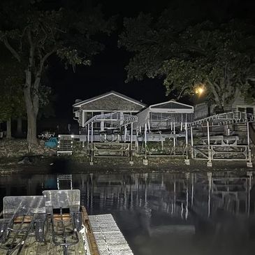 Nighttime lakeside dock with boats and waterfront homes.