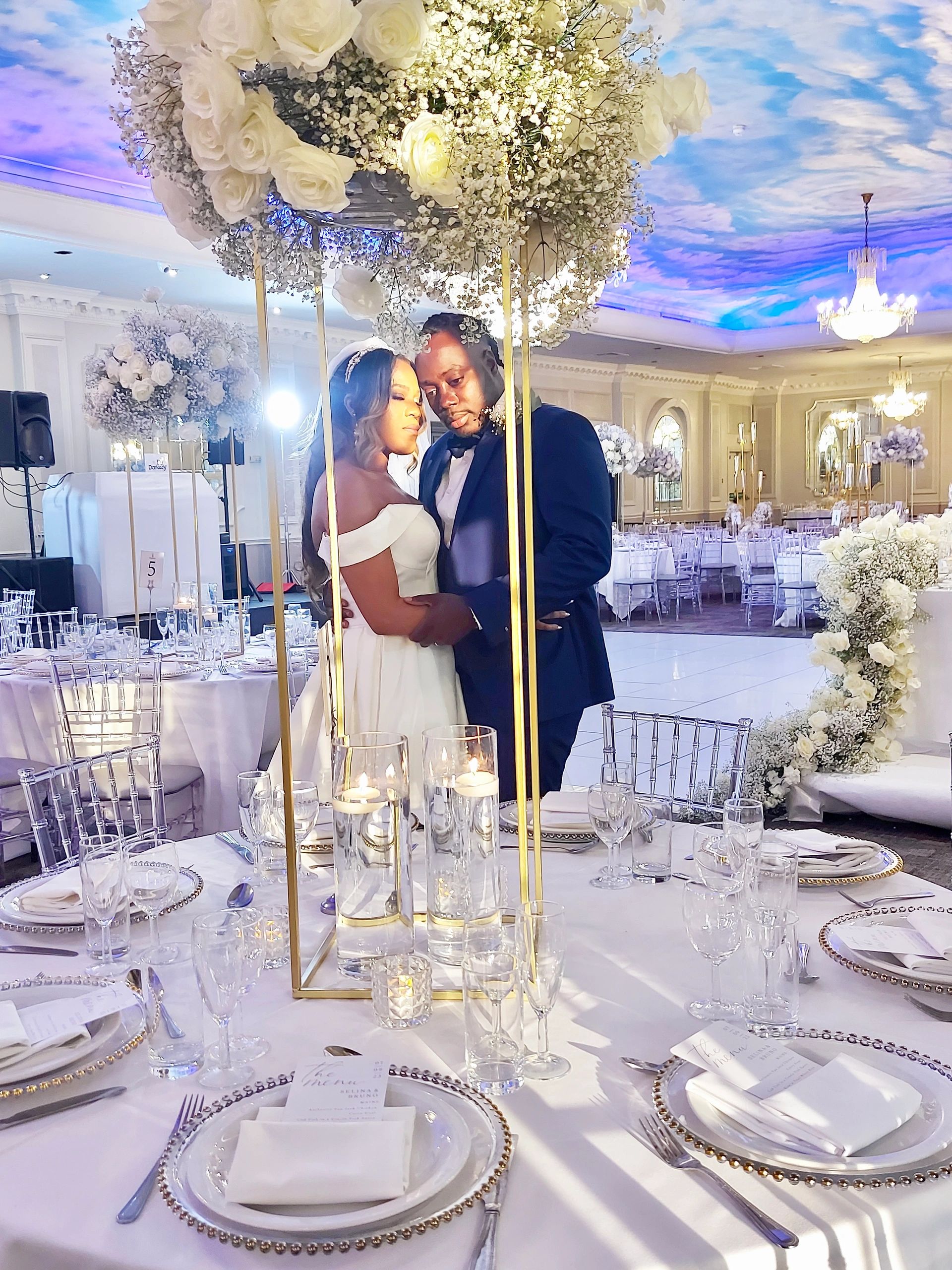 Newlyweds embrace at elegant wedding reception with floral decor.