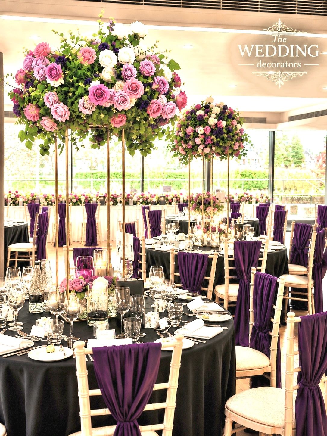 Elegant wedding setup with purple and pink floral centerpieces.