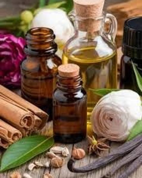 Aromatherapy essentials with oils, cinnamon sticks, and flowers on wood.