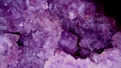 Violet, purple crystal amethyst gemstone up close in detail. Rocky, pretty, shimmering, healing
