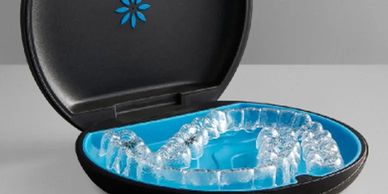 Clear dental aligner in a black and blue case.
