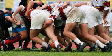 Rugby players engaged in a scrum on a grassy field.