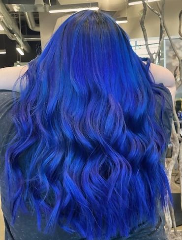 A woman is having blue color applied to her hair.