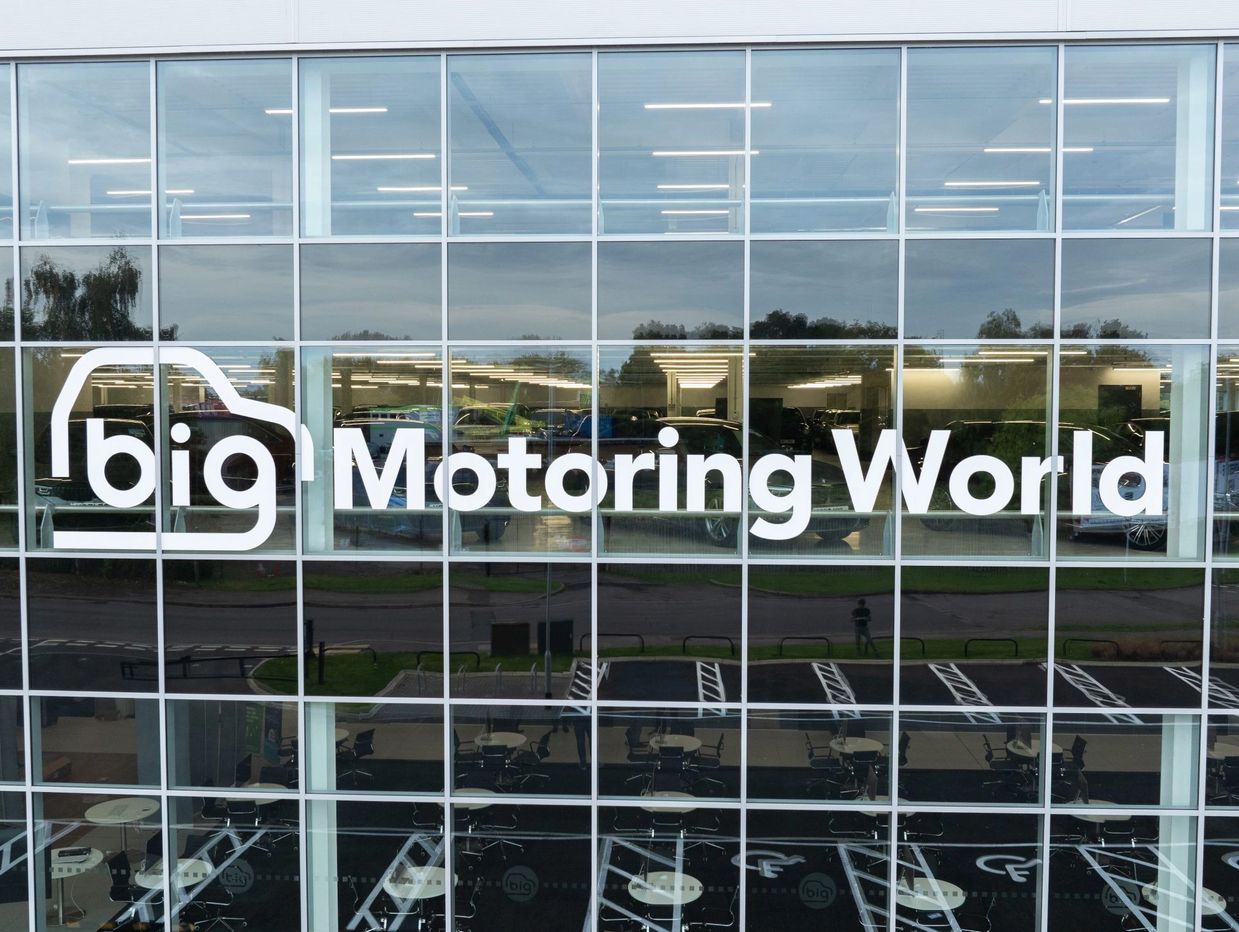 A glass window with the company name Big Motoring World on it in white letters.