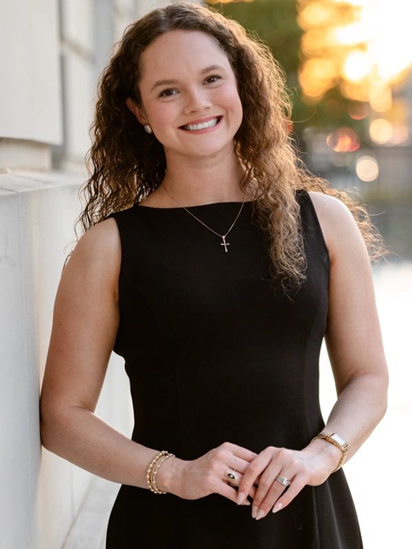 Smiling woman in a black dress standing outdoors.