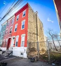 Red brick townhouse with an empty lot on the side.