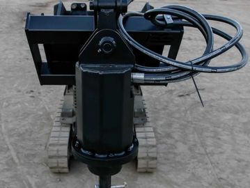Close-up of a hydraulic drill machine on a dirt ground.