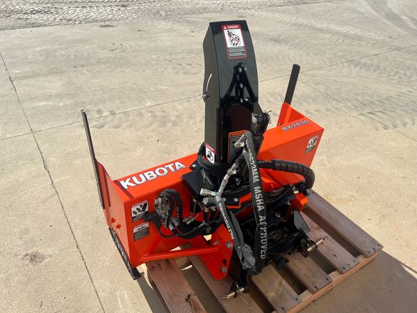 Kubota BX2830 wood chipper attachment on a wooden pallet outdoors.