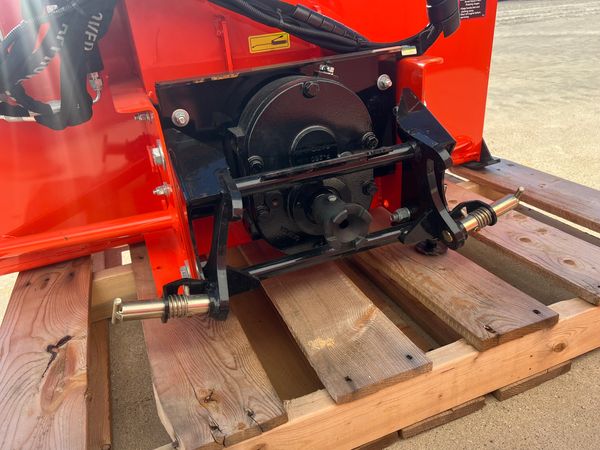 Close-up of mechanical parts on red machinery resting on wooden pallets.
