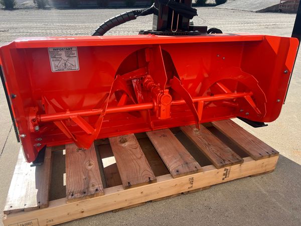 Close-up of an orange snowblower auger on a wooden pallet.