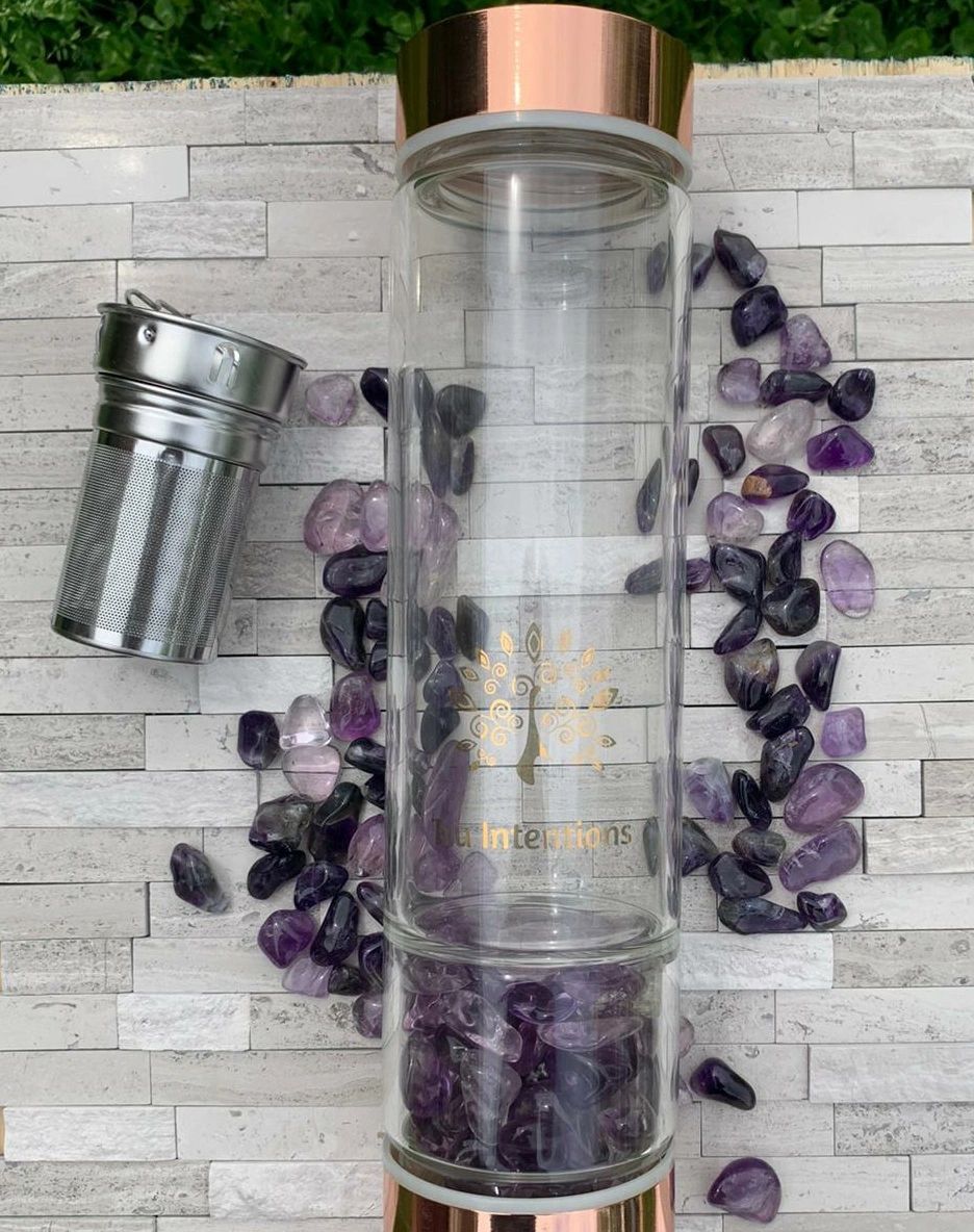 Glass infuser bottle with purple crystals in and around it.