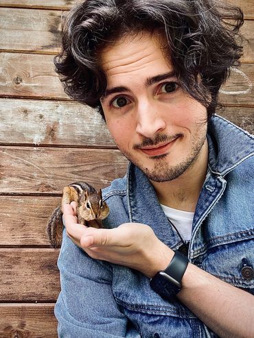 Young man holding a chipmunk on his hand.