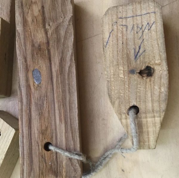 Two pieces of wood connected by a rough rope with handwritten markings on one piece.
