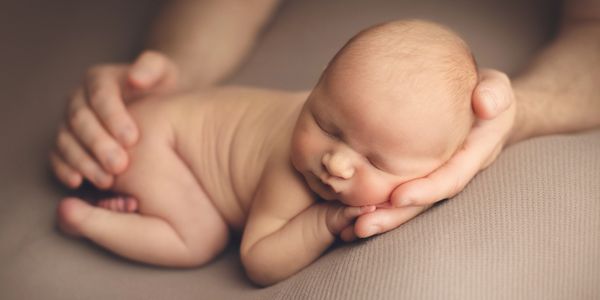 newborn baby boy sleeping on a cream background 