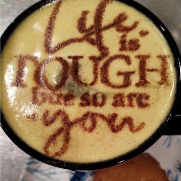 Coffee art with the motivational quote 'Life is tough but so are you.'