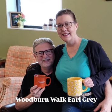 Two people holding colorful mugs, smiling indoors.
