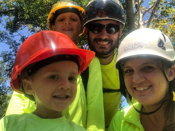 A family wearing safety helmets and bright shirts outdoors.