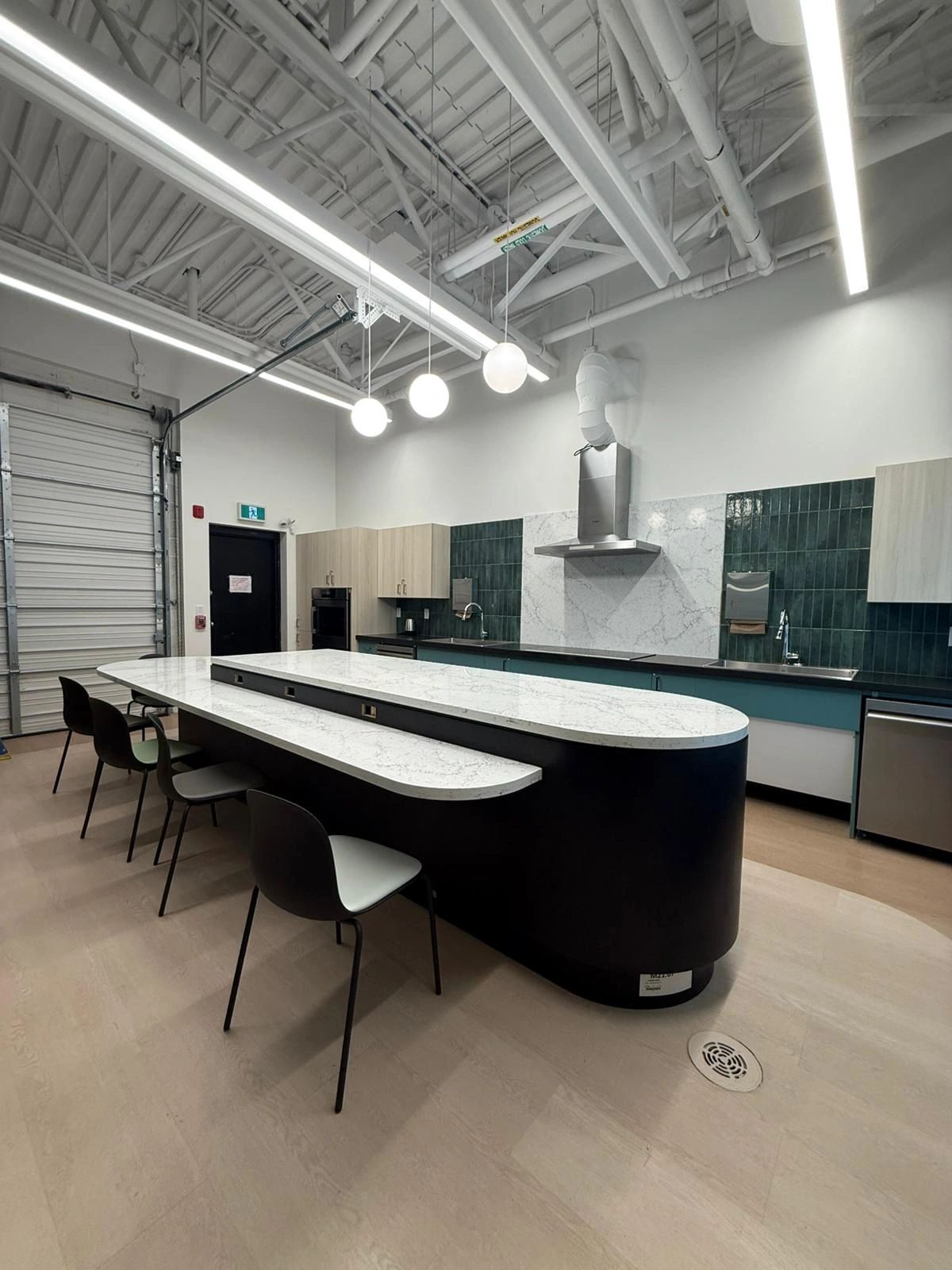 Commercial kitchen island with curved millwork and integrated appliances 