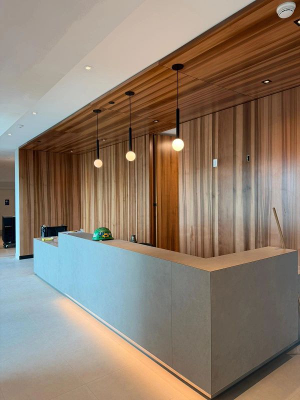 Modern reception desk with wooden wall and globe light pendants.